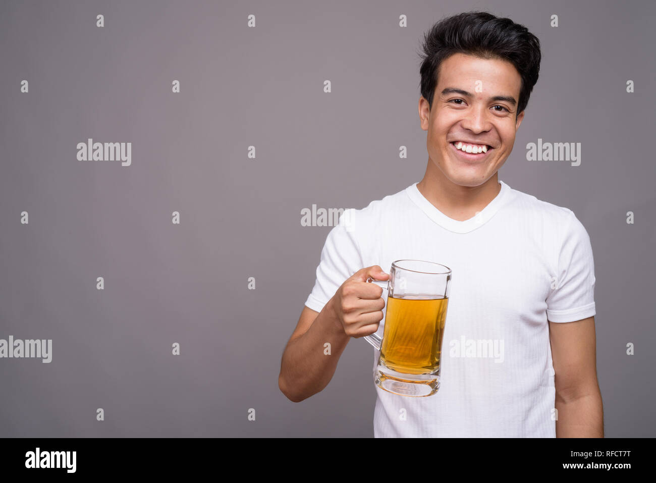 Portrait of young Asian man against gray background Stock Photo