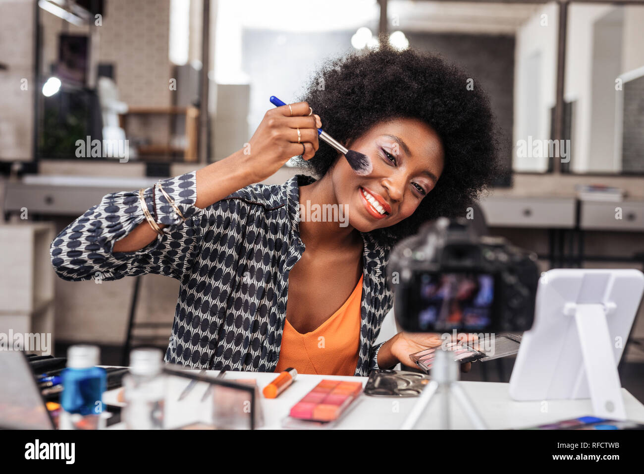 Pretty dark-skinned woman with bright makeup feeling amused Stock Photo
