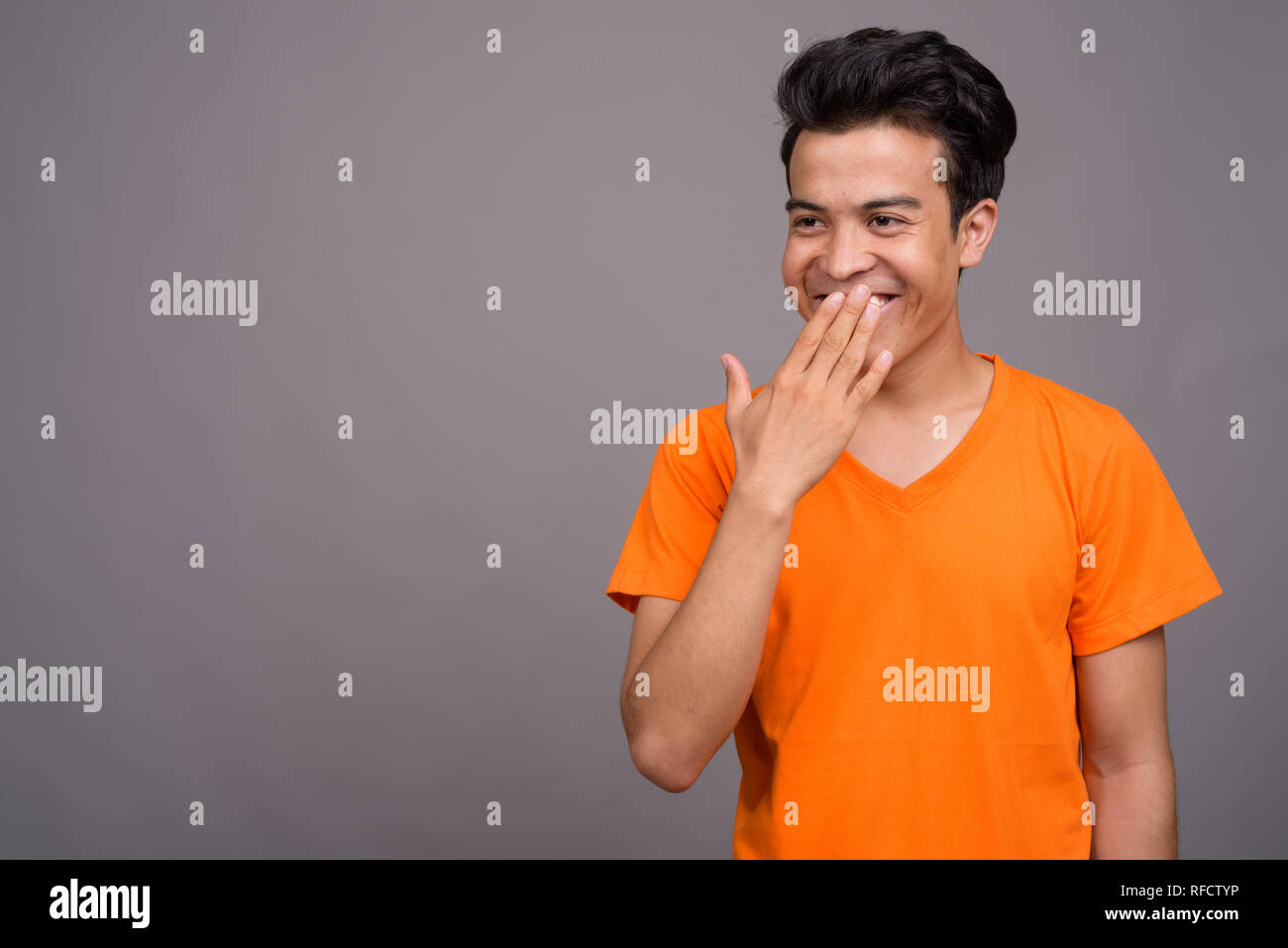 Portrait of young Asian man against gray background Stock Photo