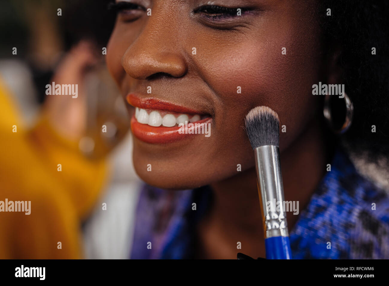 Pretty beaming dark-eyed model in an orange top smiling happily Stock Photo