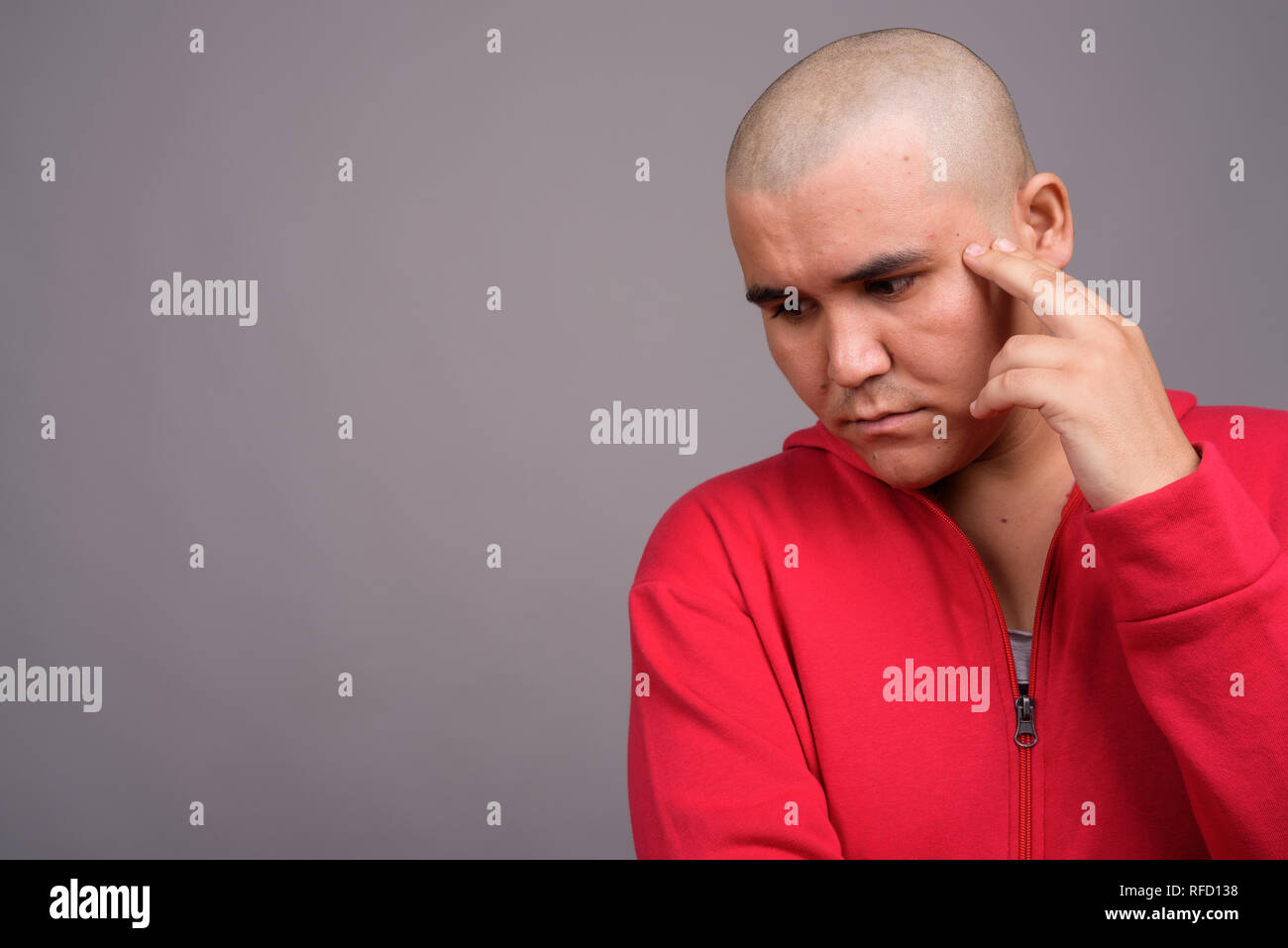 Young bald Asian man against gray background Stock Photo