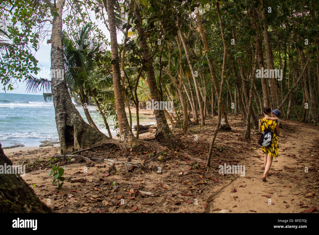 A photo of a woman and son walking on a hiking trail close to a beautiful beach with turquoise blue water at Manzanillo National Park, Costa Rica Stock Photo