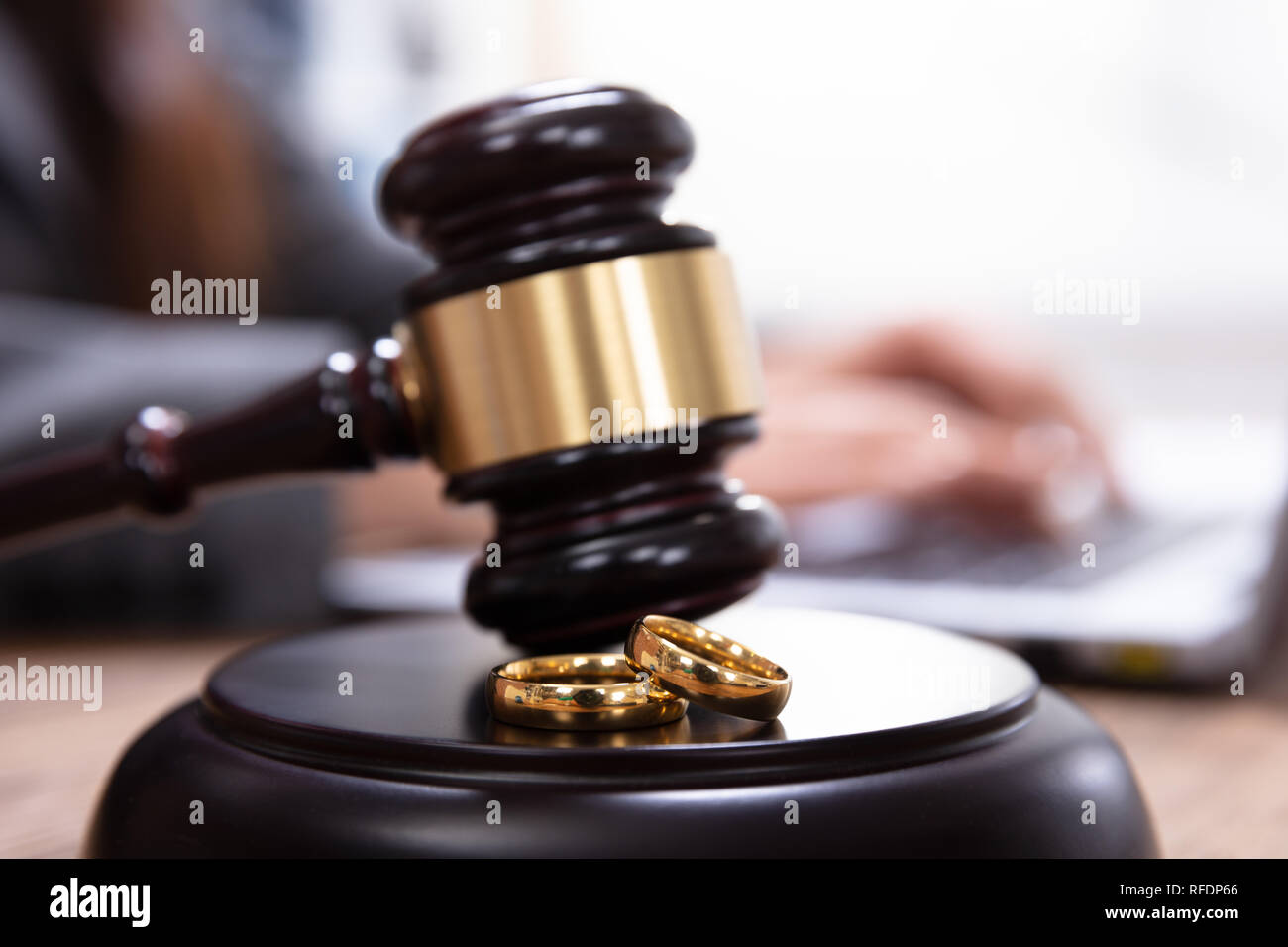 Closeup Of Golden Wedding Rings On Wooden Mallet At Table In Courtroom Stock Photo