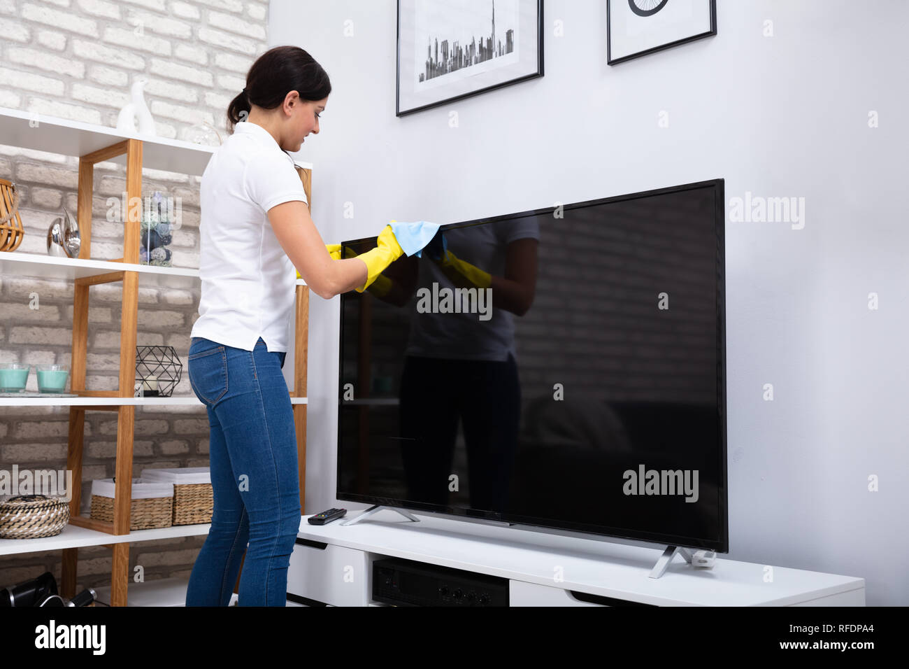 Close-up Of Woman Using Cloth To Clean The Television At Home Stock Photo