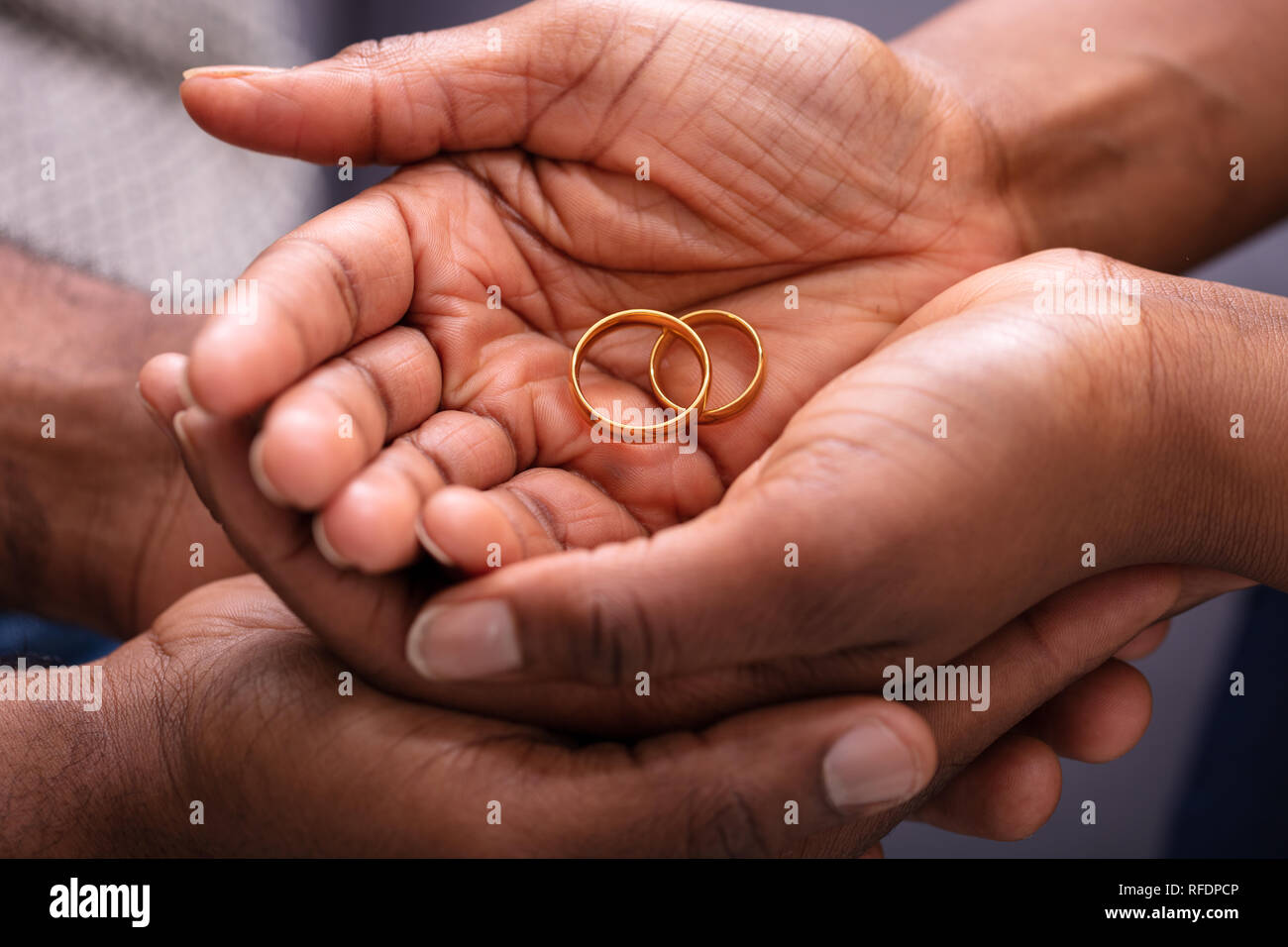 Man And Woman's Hand With Pair Of Golden Engagement Rings Stock Photo