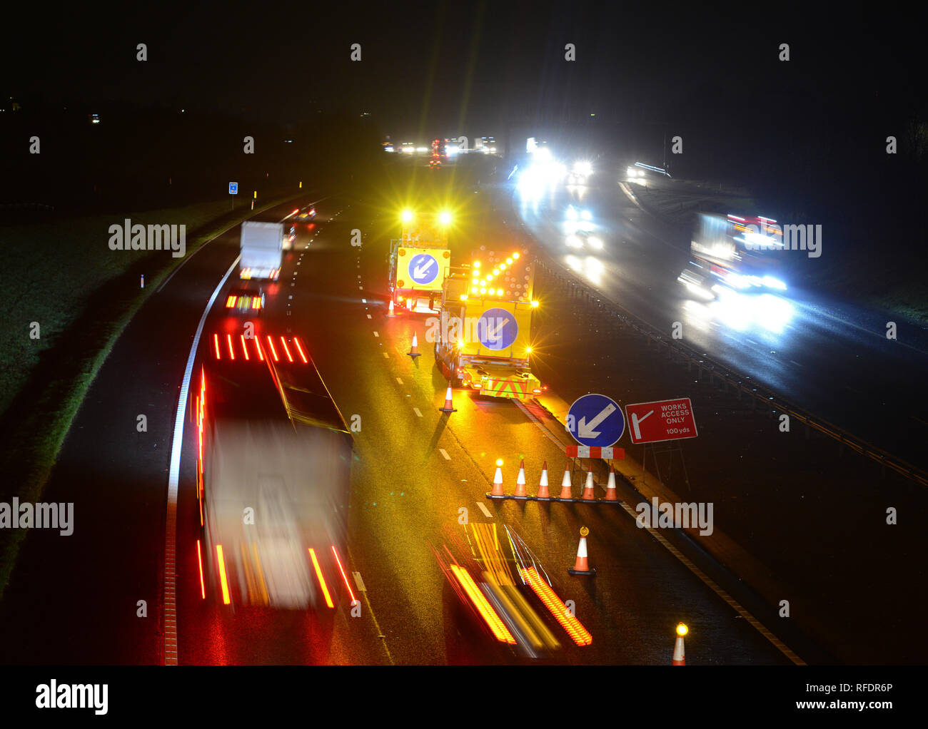 road workers with warning vehicles with flashing arrows closing lane at