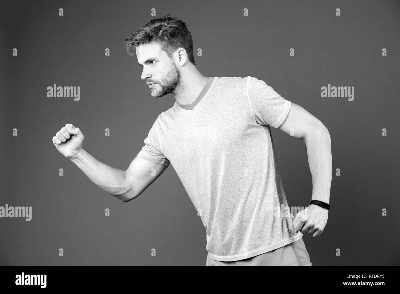 Man in tshirt and shorts on violet background. Runner in blue casual clothes on purple background. Sportsman in active wear for running. Sport fashion style and trend. Fitness and gym activity. Stock Photo