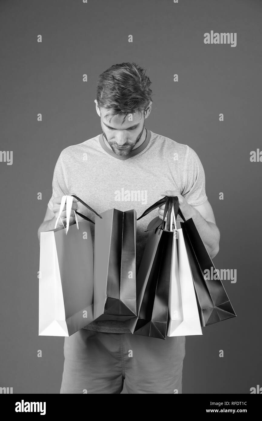 Fashion shopper look in paperbag. Man with shopping bags on violet background. Macho with colorful paper bags. Holidays preparation and celebration. Shopping or sale and cyber monday. Stock Photo