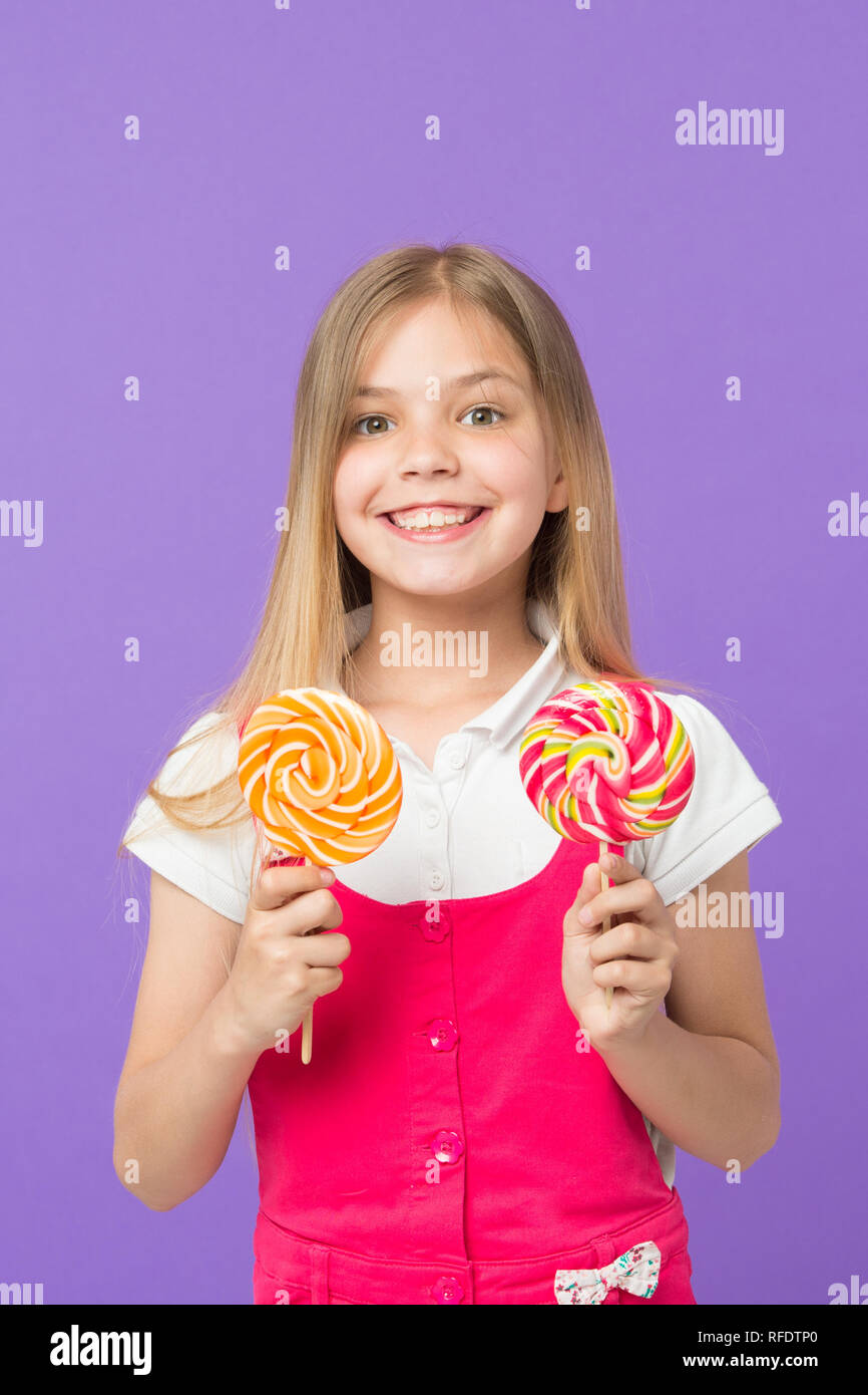 Girl eating big candy on stick or lollipop. Sweet childhood concept