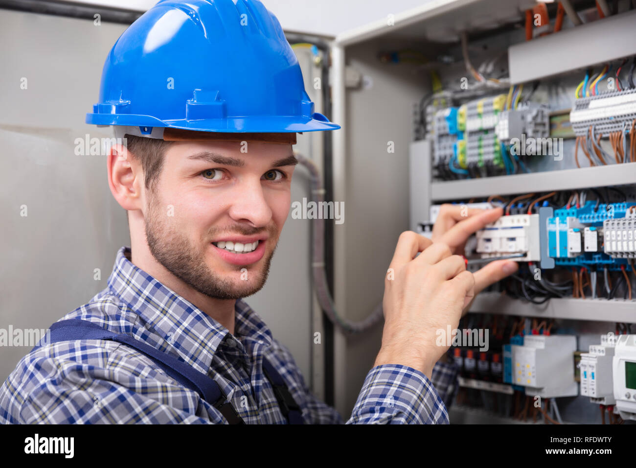 Side View Of Young Technician Repairing Fuse Box With Screwdriver Stock Photo