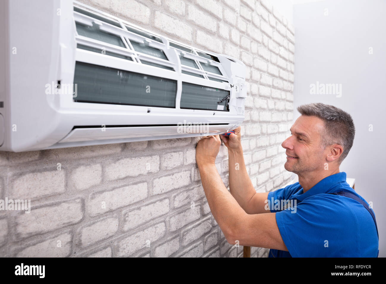 Mature Male Technician Fixing Air Conditioner With Screwdriver Stock Photo