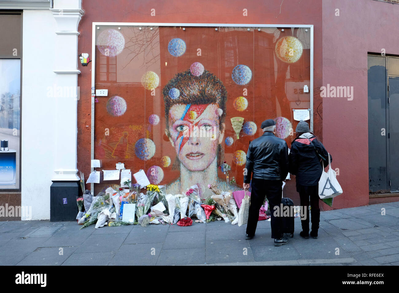 A couple looking at David Bowie mural in Brixton, London Stock Photo
