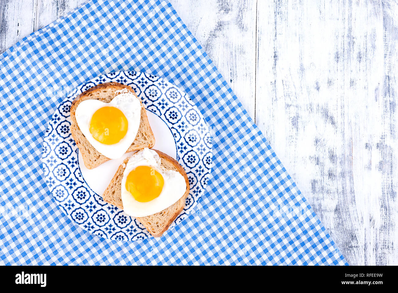 Breakfast of 2 fried heart shaped eggs. Romantic morning surpriiz on holiday. Valentine's day concept. Copy space, Flat lay Stock Photo