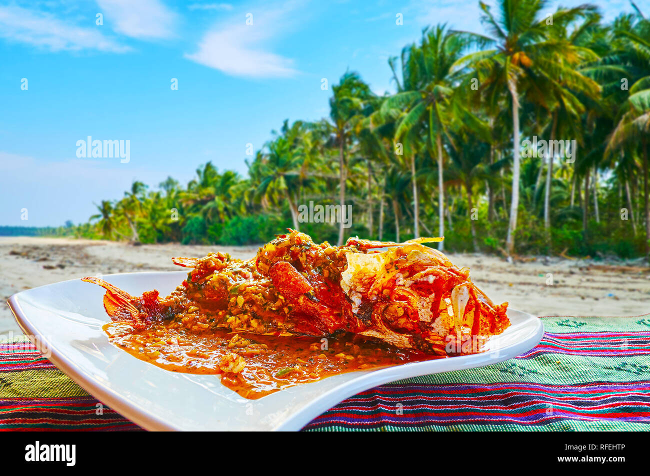 Enjoy Burmese cuisine on the picnic in Chaung Tha resort with local visit card - the fried fish in spicy sauce, vegetables and fragrant herbs, Myanmar Stock Photo