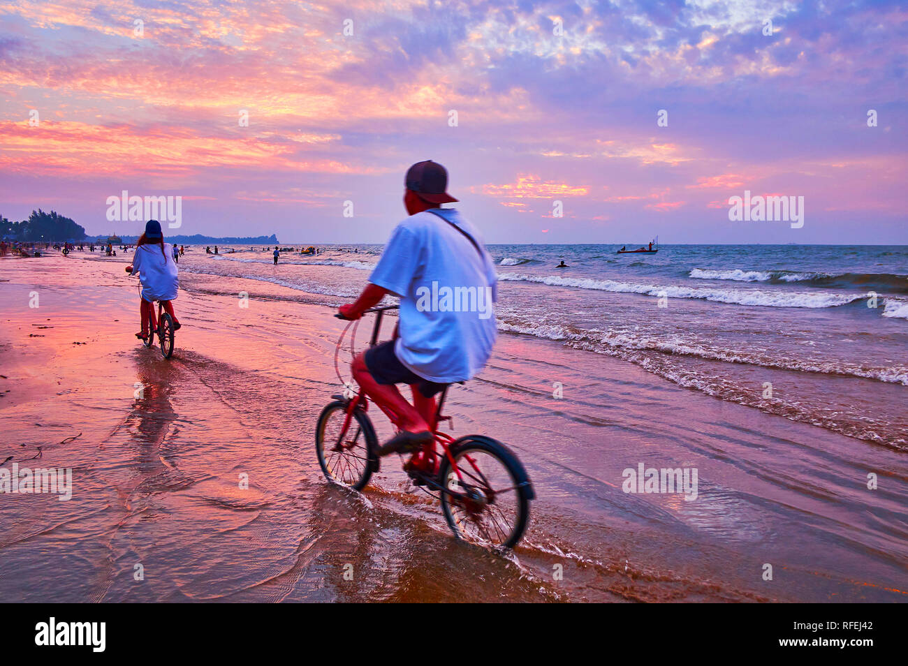 The cyclers enjoy the beach on Bay of Bengal, riding along the swash line on sunset, Chaung Tha, Myanmar. Stock Photo