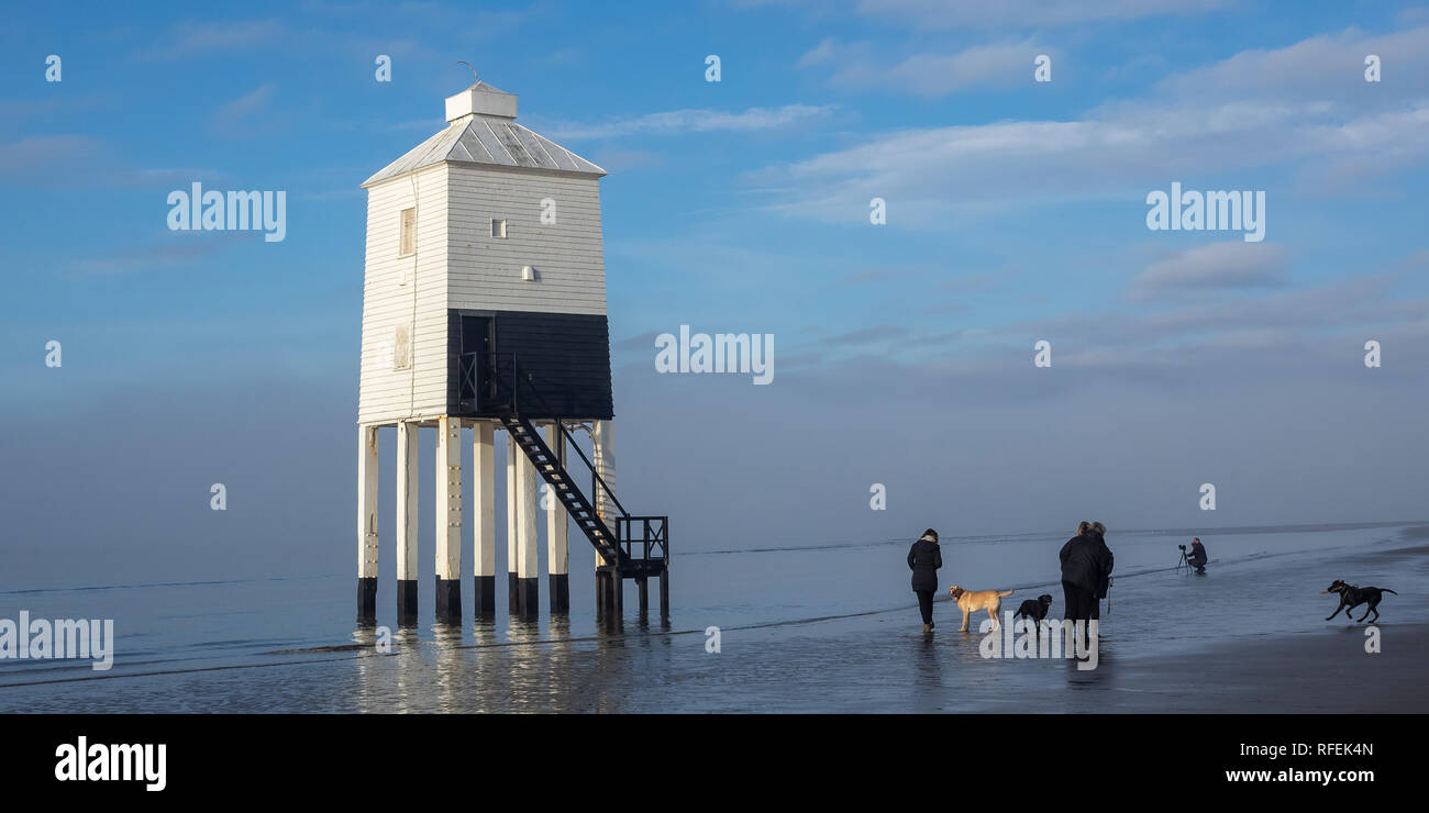 People with dogs, dog walkers and a photographer enjoy the Low Lighthouse and beach as the morning mist is burnt off. Burnham on Sea, Somerset. Stock Photo