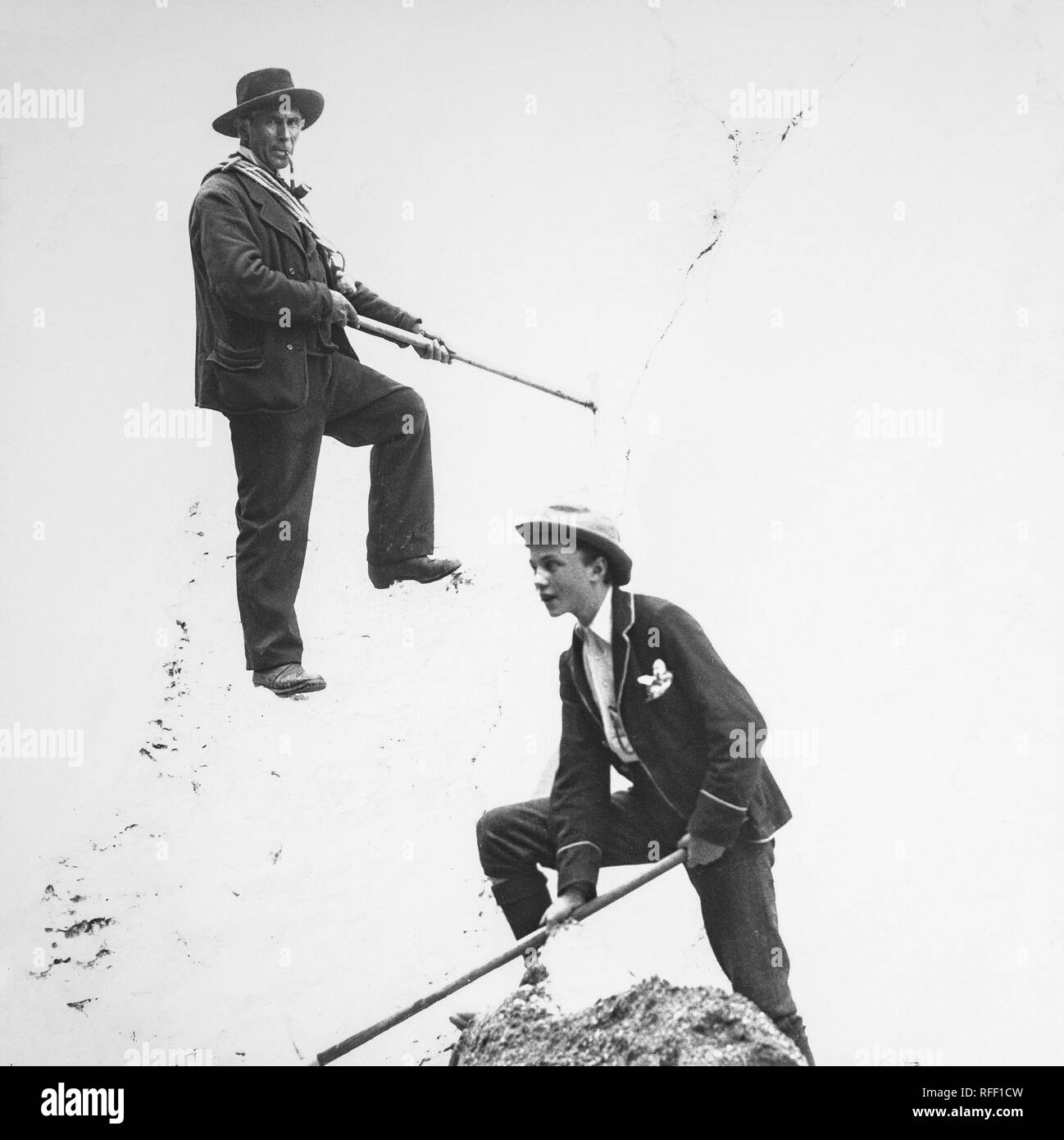 A late 19th century black and white photograph showing the famous Swiss mountain guide, Peter Kaufmann. Peter Kaufmann (January 17, 1858, in Grindelwald - October 14, 1924, in Grindelwald, at age 66) was a Swiss mountain guide during the Silver Age of Alpinism (1865-1882) and the early twentieth century, who guided amateurs, experienced climbers, and several notables across glaciers, over mountain passes, and to the summits in the Swiss Alps, the Canadian Rockies, and the Selkirks. A younger male can be seen on the snow slope just below him. Stock Photo