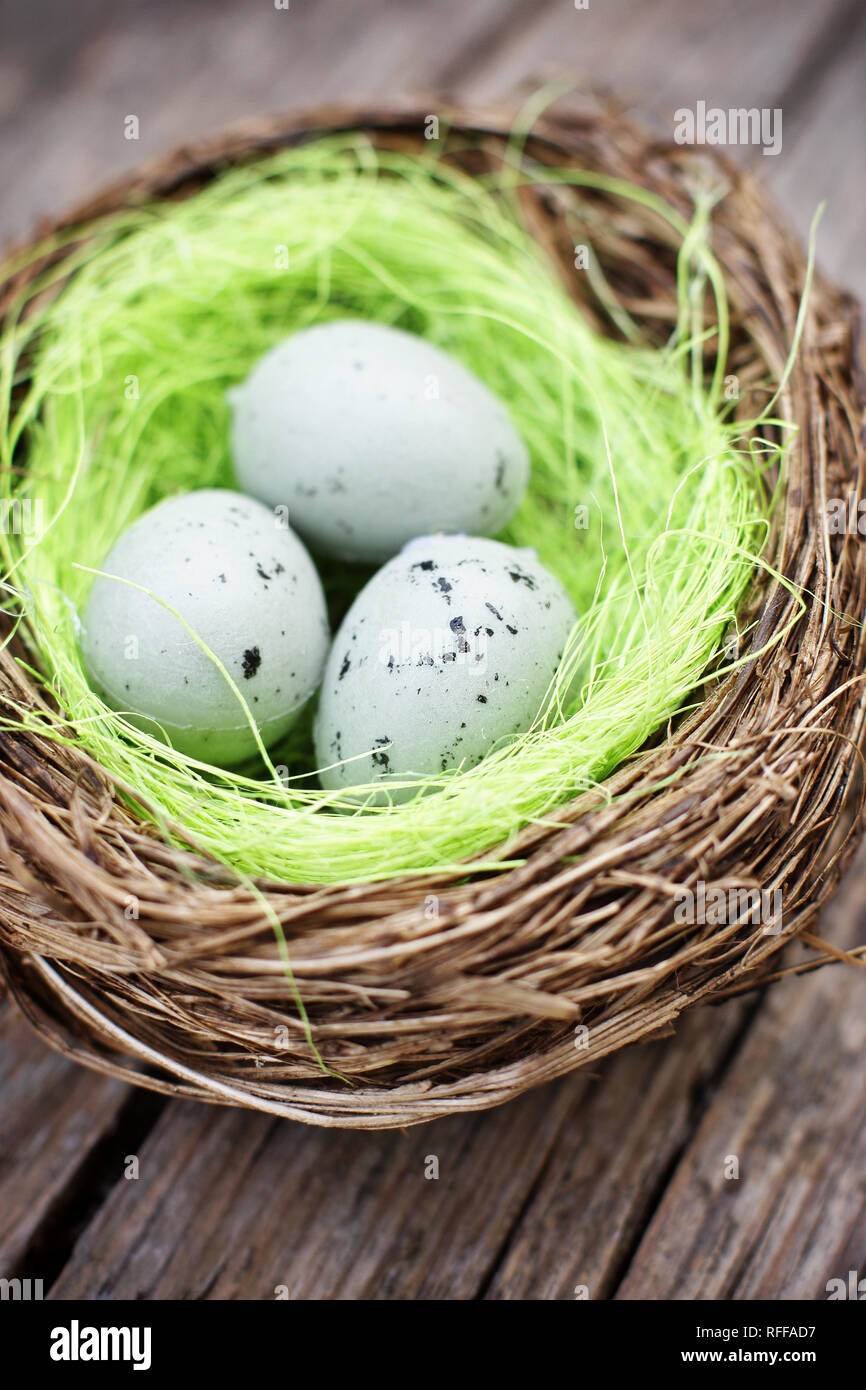 Three little eggs in bird nest on wooden table Stock Photo - Alamy