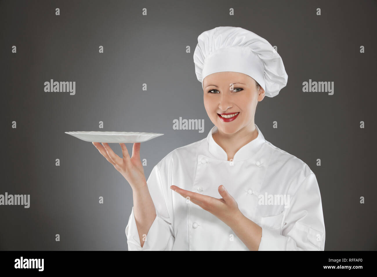 Female chef holding empty plate Stock Photo