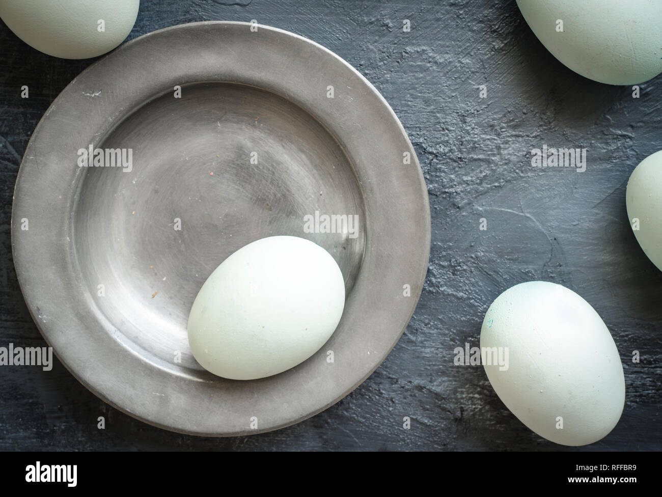 Eggs, raw flat lay, pewter dish, dark food Stock Photo