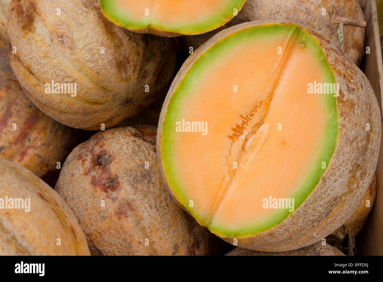 Bunch of organic cantaloupes, and one cut in half showing its orange flesh, displayed on sale on farmer's market stand in Serbia, detail Stock Photo