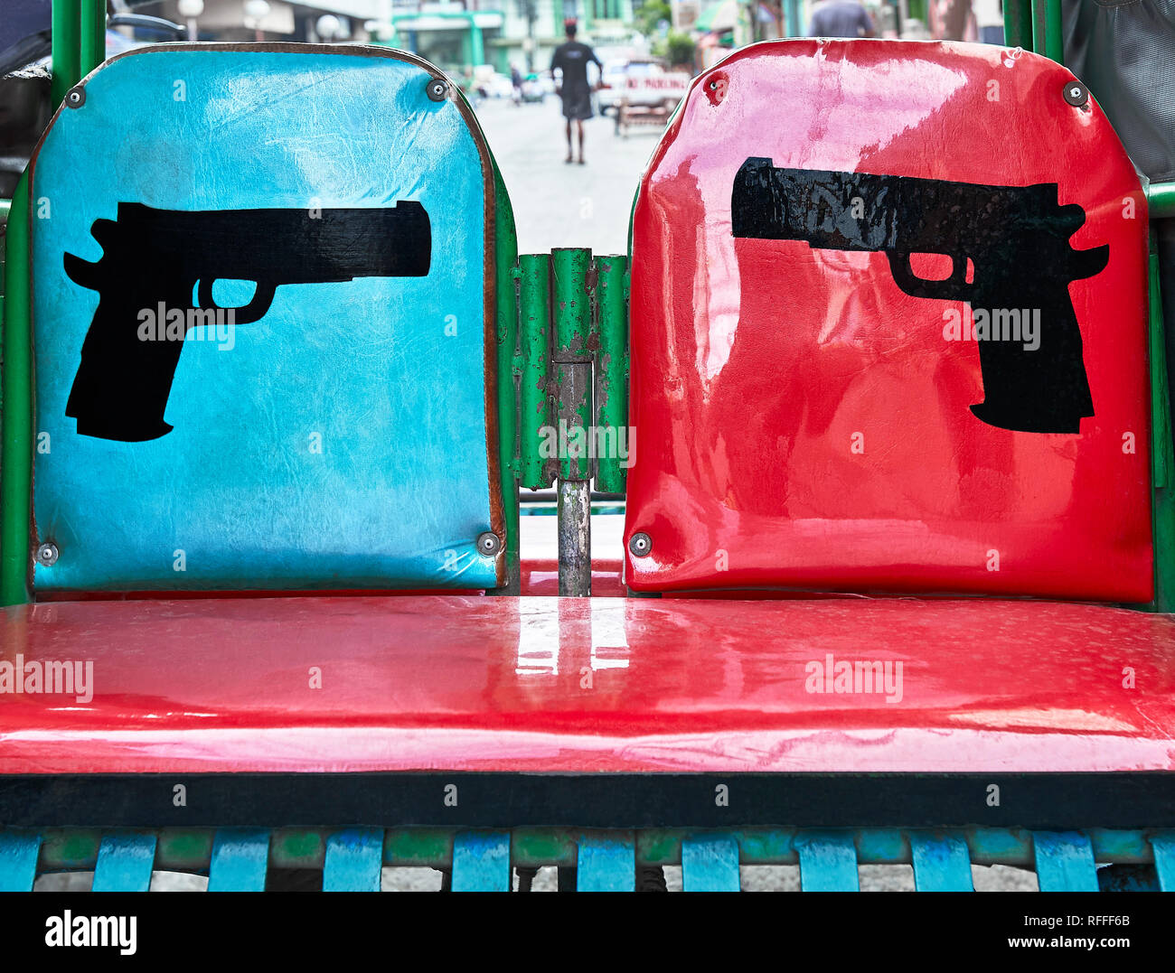 Seats of a pedicab, bicycle with sidecar, decorated with two guns facing each other, seen in Iloilo City, Philippines Stock Photo
