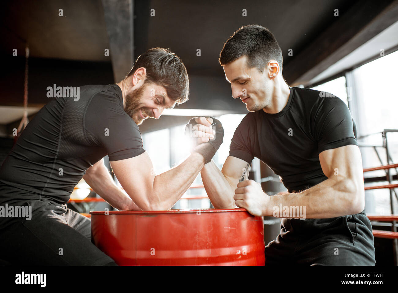 Two young athletes in black sportswear having a hard arm wrestling