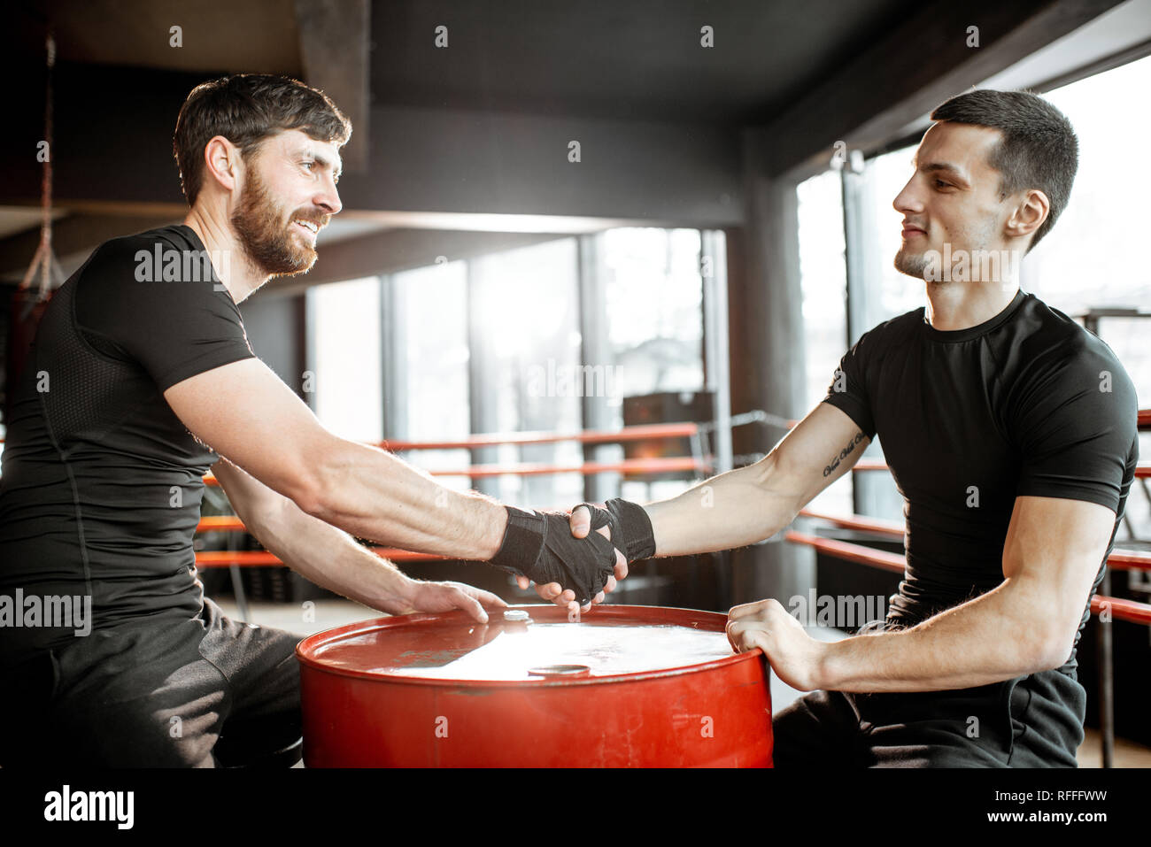 Two young athletes handshaking before fighting in the boxing ring at
