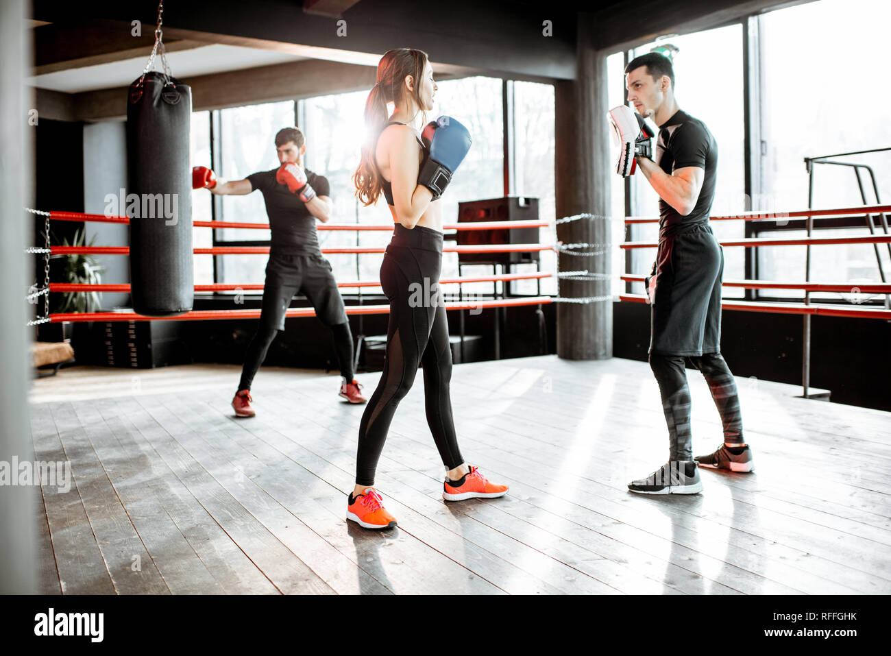 Young woman training to box with personal coach on the boxing ring at