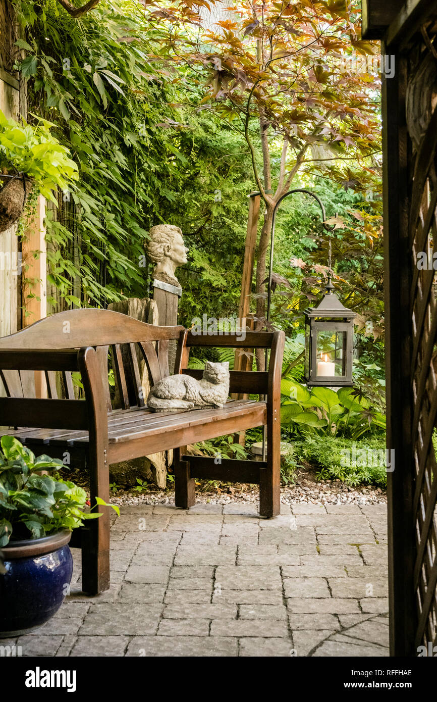 Garden path with wooden bench and garden ornaments. Stock Photo