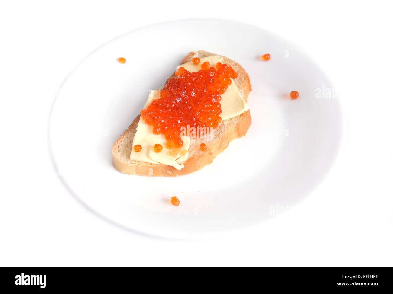 Sandwich with butter and red salmon caviar on white bread lies on a round plate, isolated on white background top view Stock Photo