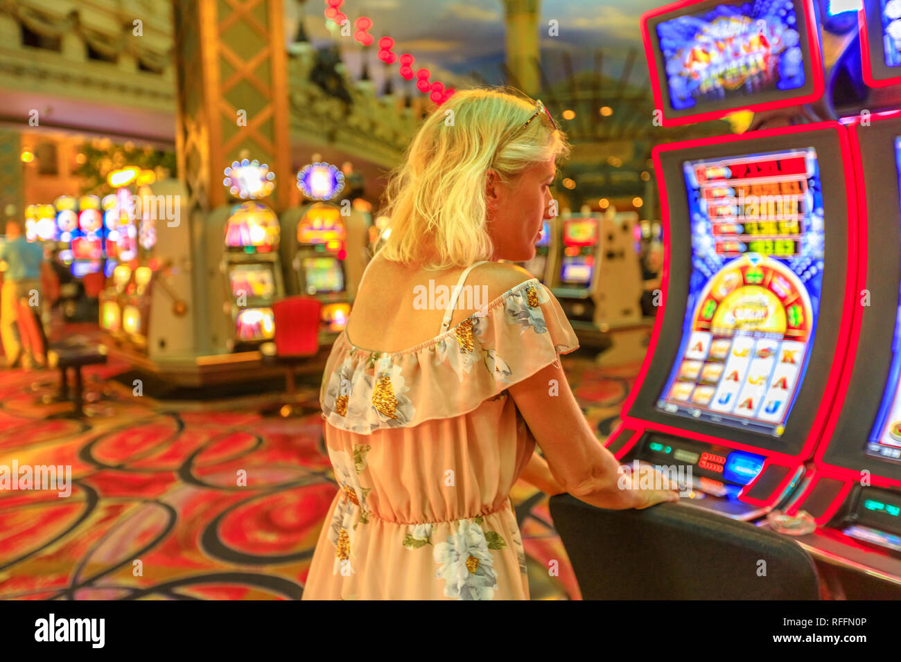 Caucasian woman gambling in casino playing on slot machines spending money. Gambler addict concept. Blonde girl play in hotel casino in Las Vegas Stock Photo