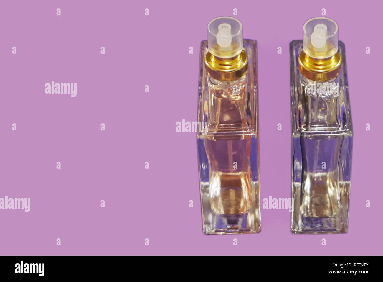 Two glass bottles with perfume on the lilac background with free copy space for text Stock Photo