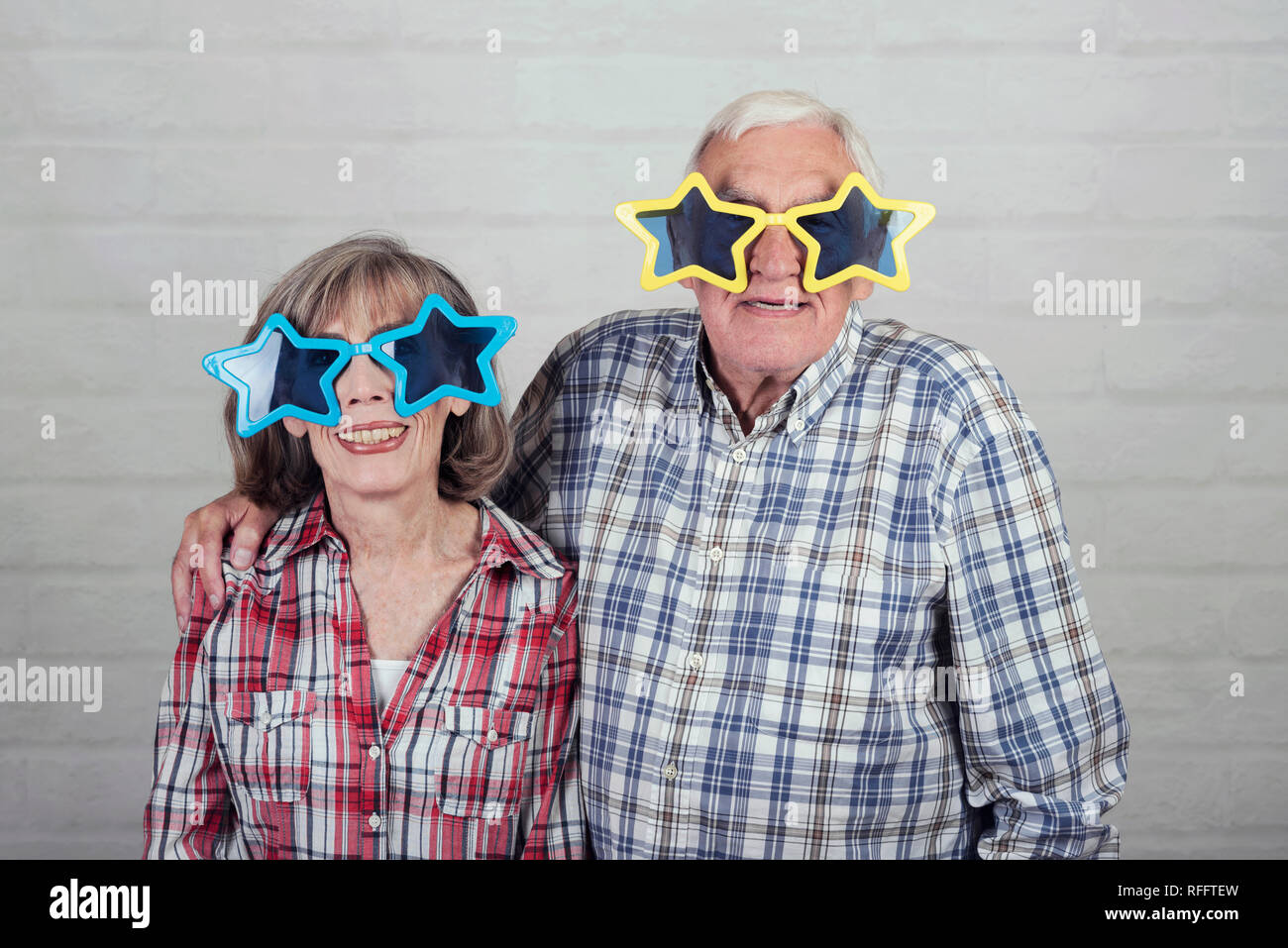 funny grandparents with big star glasses on brick background Stock Photo