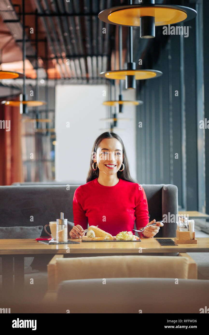 Cheerful beautiful woman with red lips eating breakfast in restaurant Stock Photo