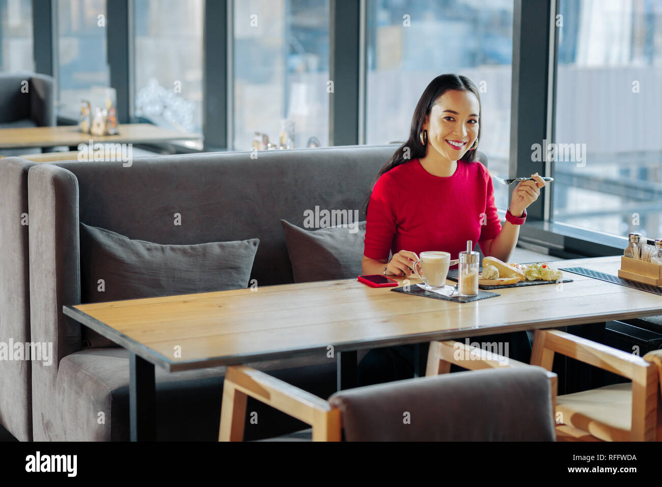 Cheerful businesswoman with red lips having rest in restaurant Stock Photo