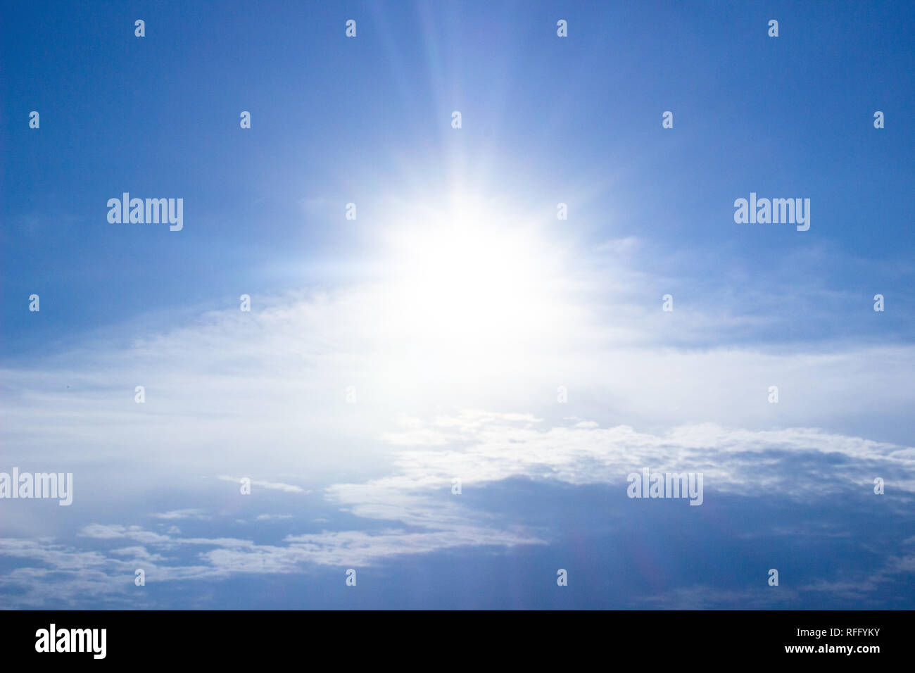 Sun shining in the bright blue sky, above the clouds Stock Photo
