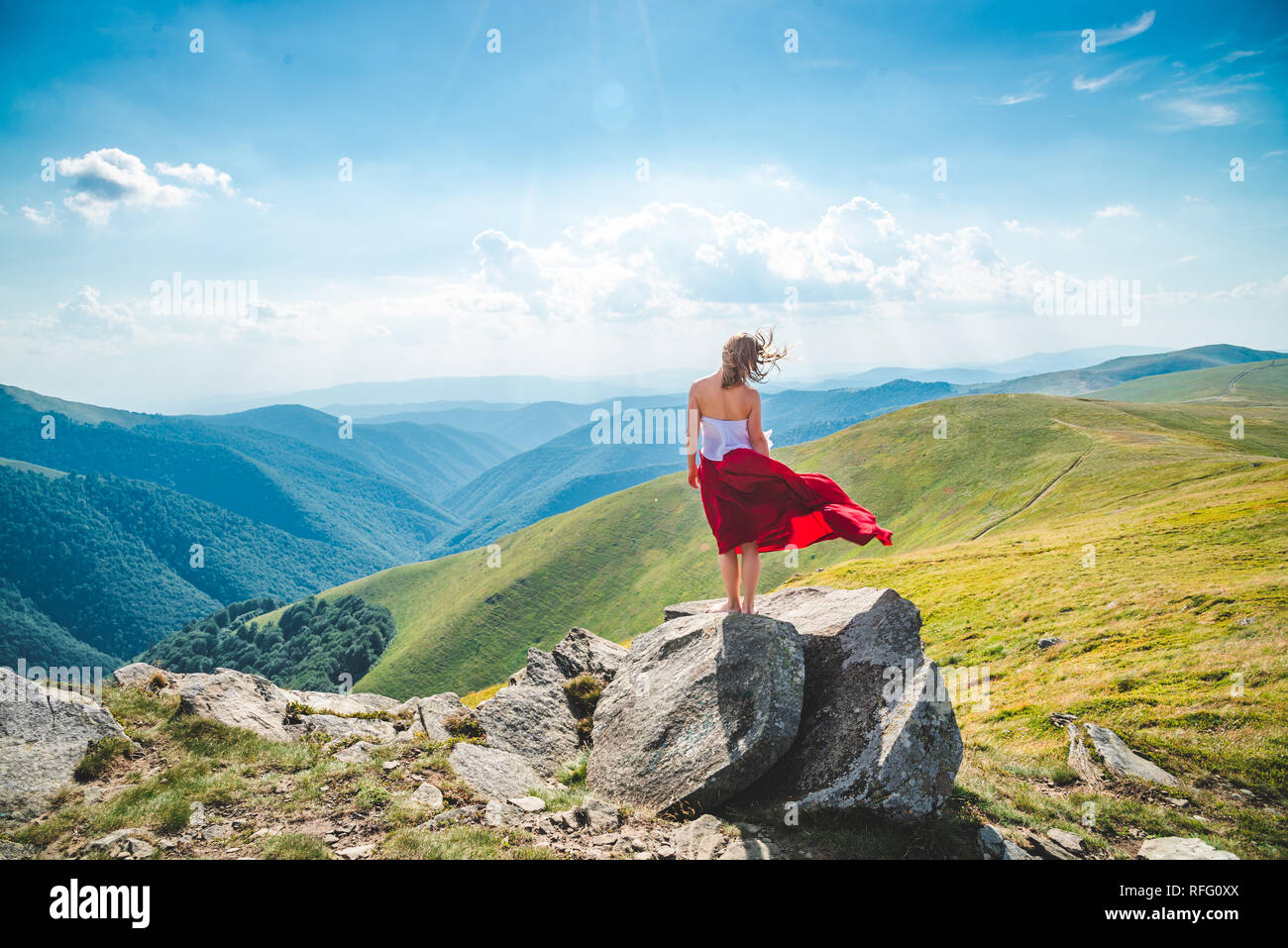 Young woman in red dress staying on the top of mountain Stock Photo - Alamy