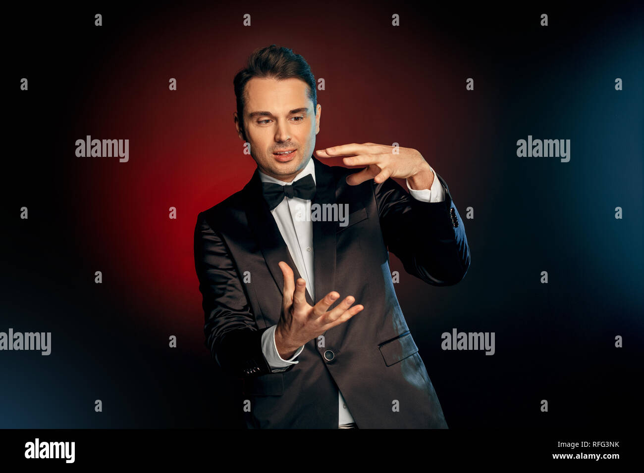 Professional Occupation. Showman in suit standing isolated on wall showing trick impressed Stock Photo