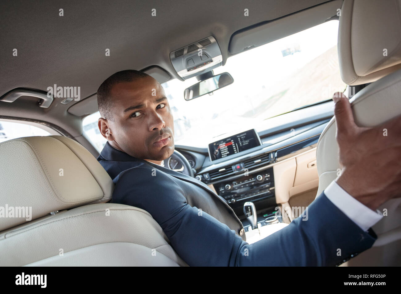 Young security guard driver sitting inside car looking back angry back