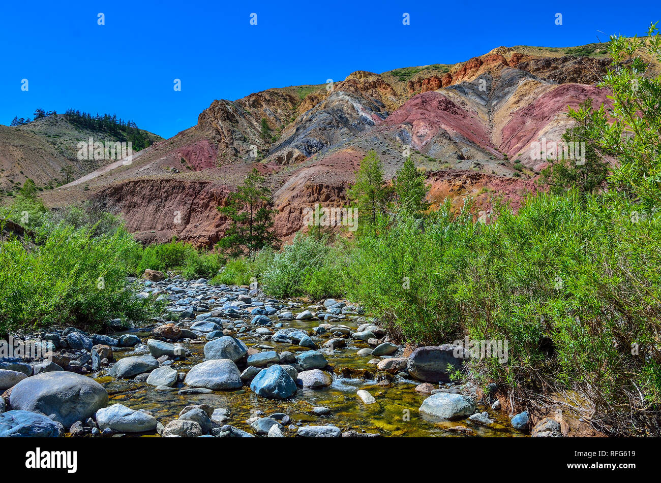 View of unrealy beautiful colorful clay cliffs in Altai mountains, Russia. Summer landscape, which is called Martian and creek running between stones  Stock Photo