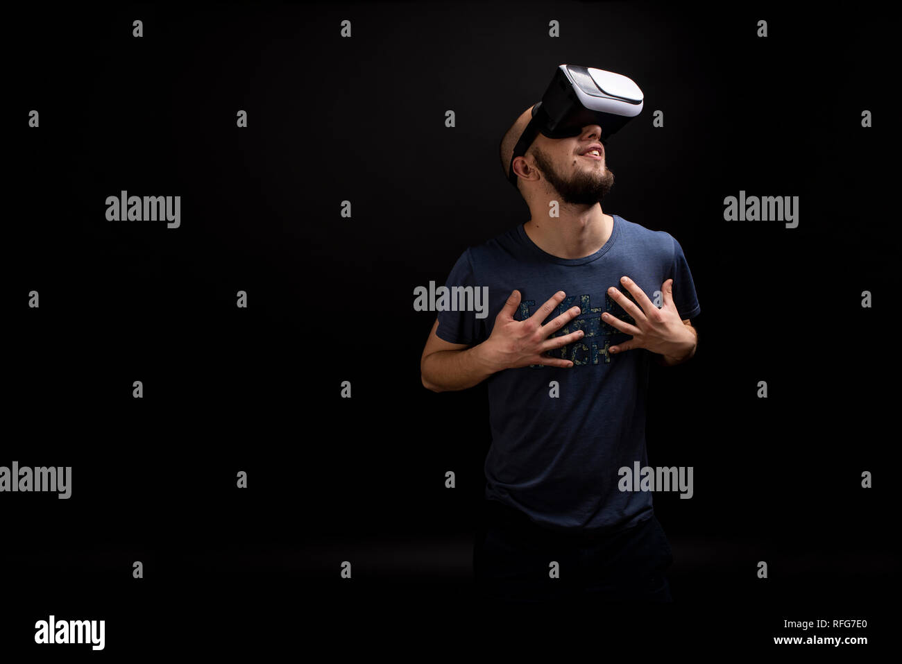 Male touching chest with both hands while using a VR gadget. Hi-tech futuristic innovation portrait shot in studio. Copy space available Stock Photo
