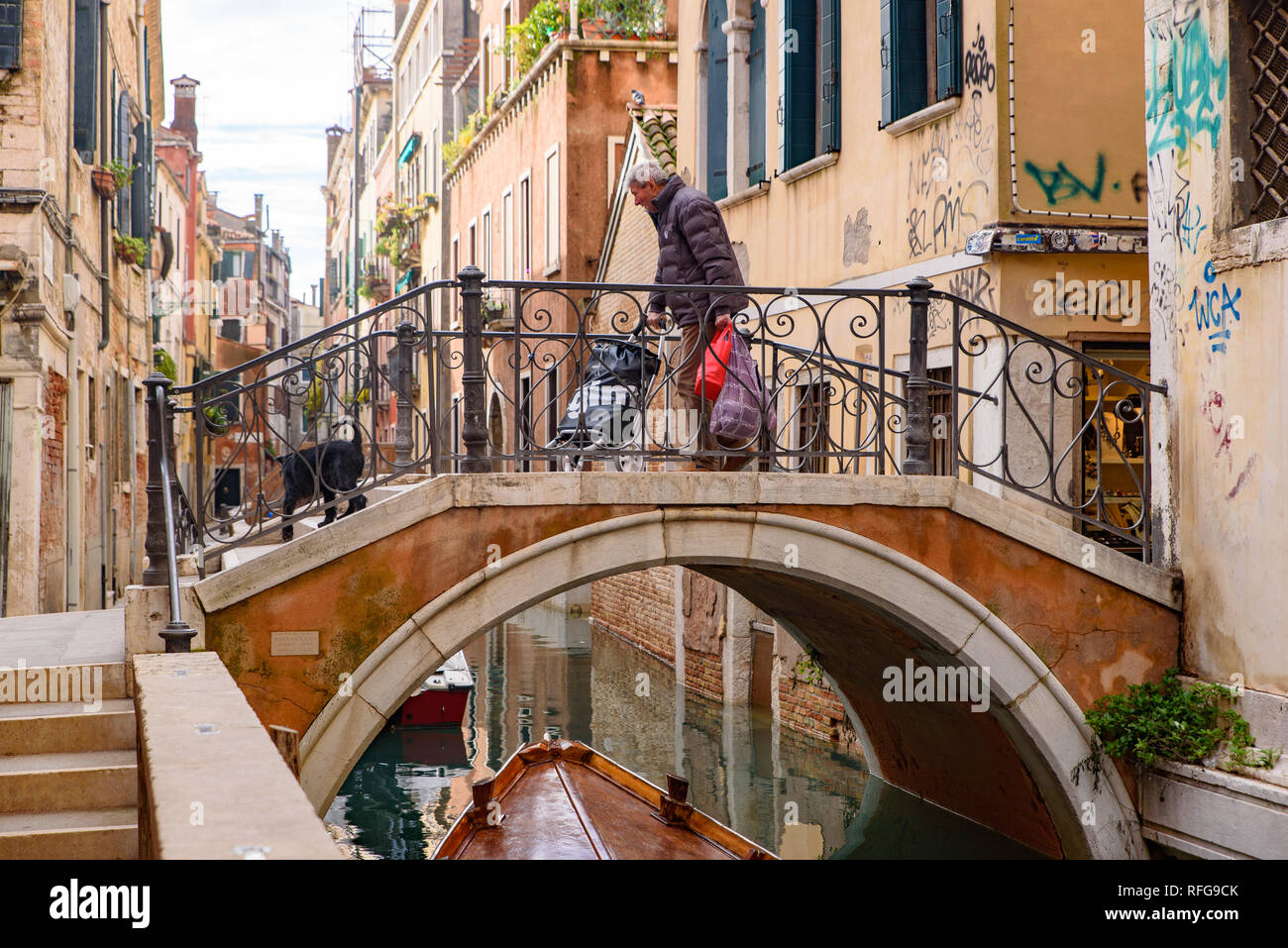 An old man passing the bridge on canal, Venice, Italy Stock Photo