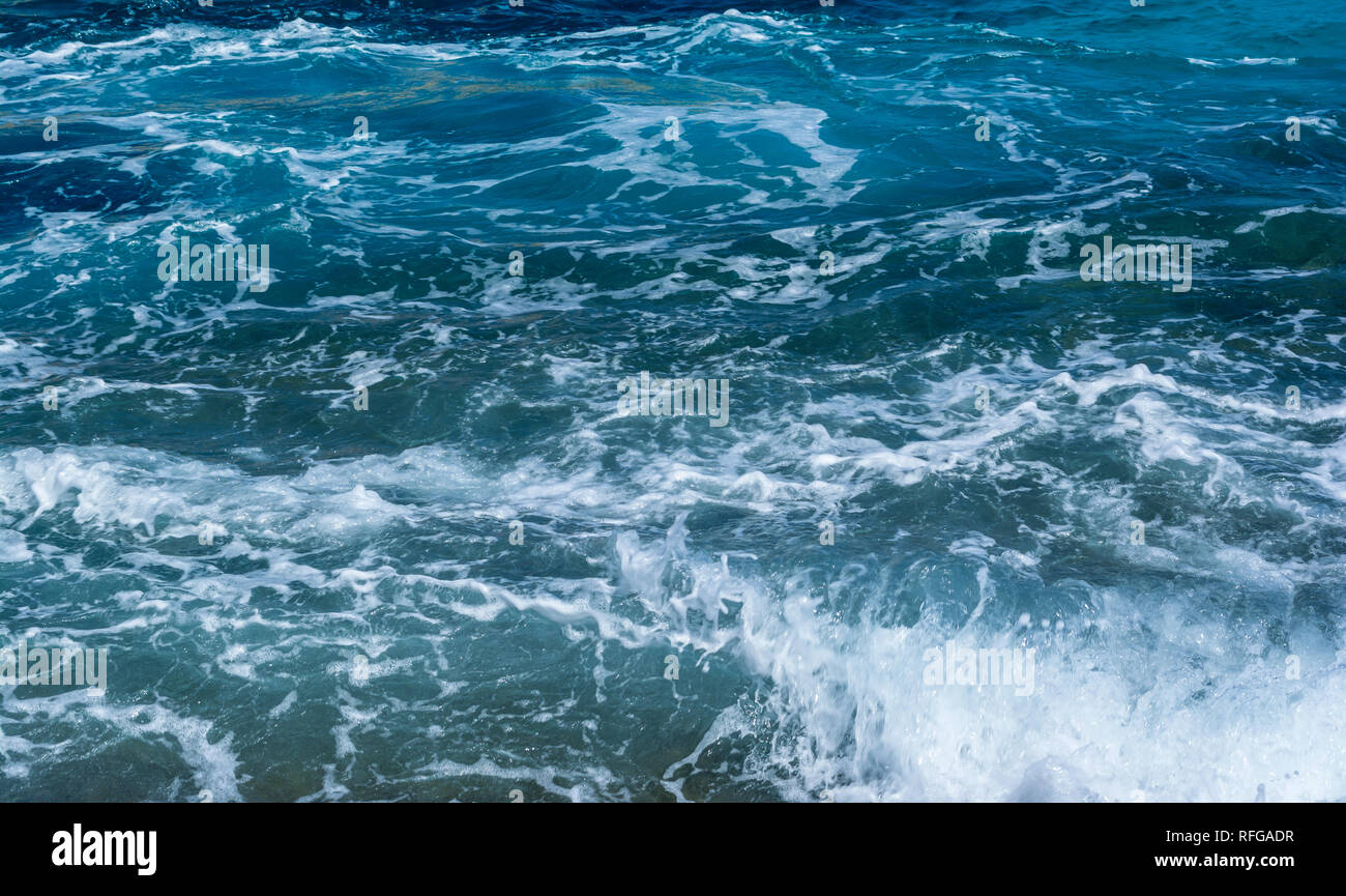 surface of the blue sea water with white foam on sunny day - wave ...