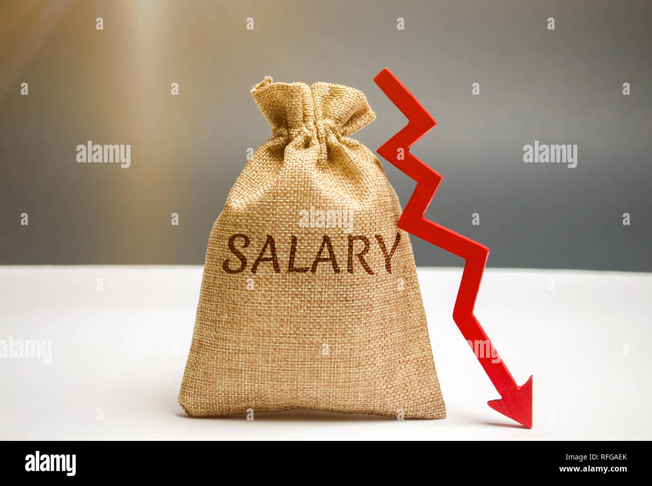 Money bag with the word Salary and arrow to down. lower salary, wage rates. demotion, career decline. lowering the standard of living. wage cuts. decr Stock Photo
