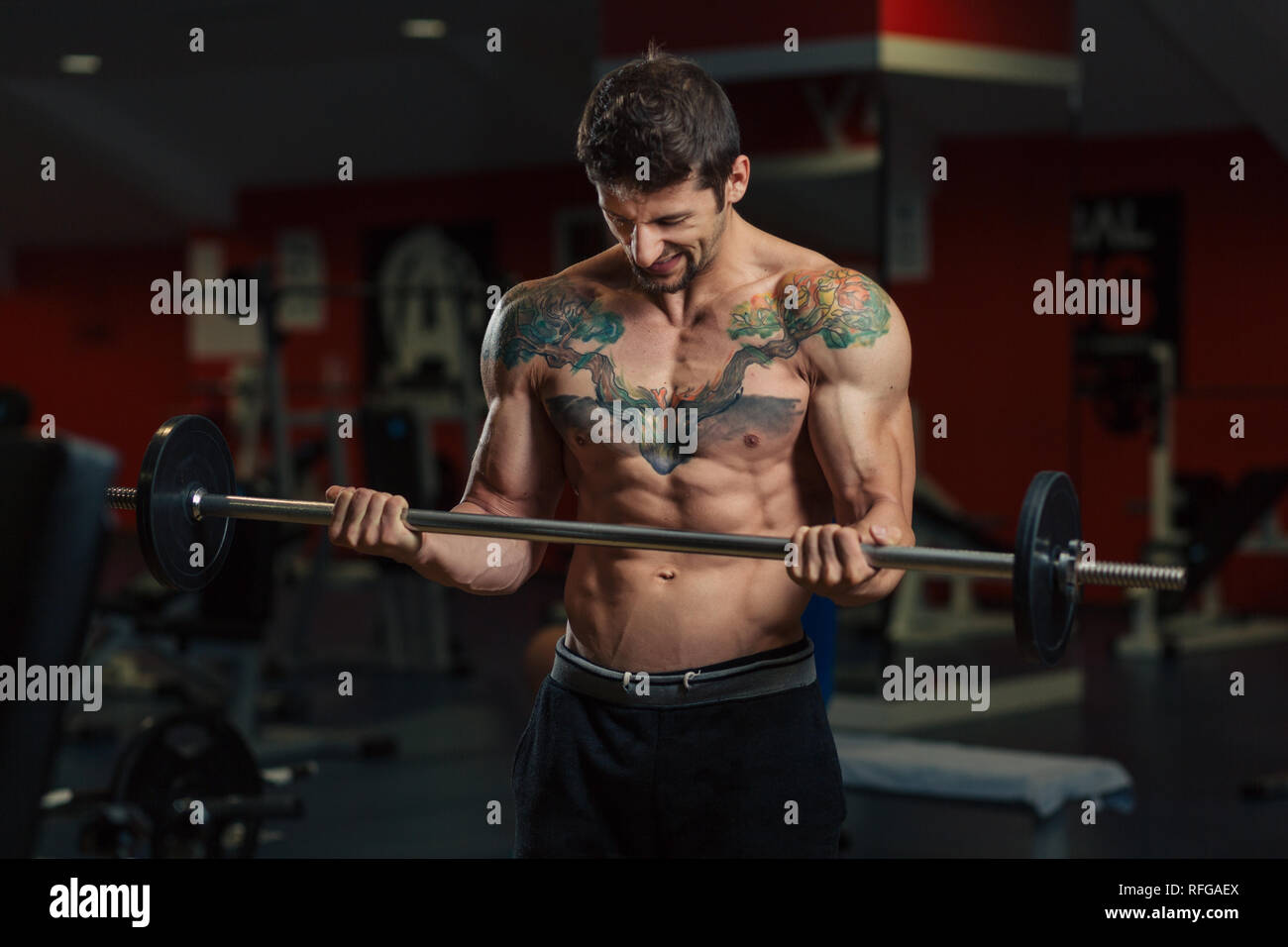 Very fit man with low body fat in the gym doing biceps curl exercise