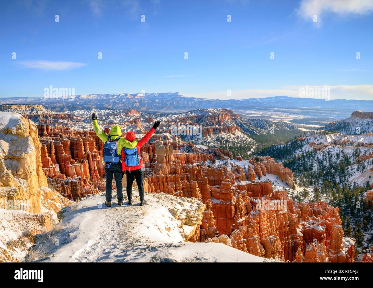 Tourists with outstretched arms overlooking the amphitheatre, bizarre snow-covered rocky landscape with Hoodoos in winter Stock Photo