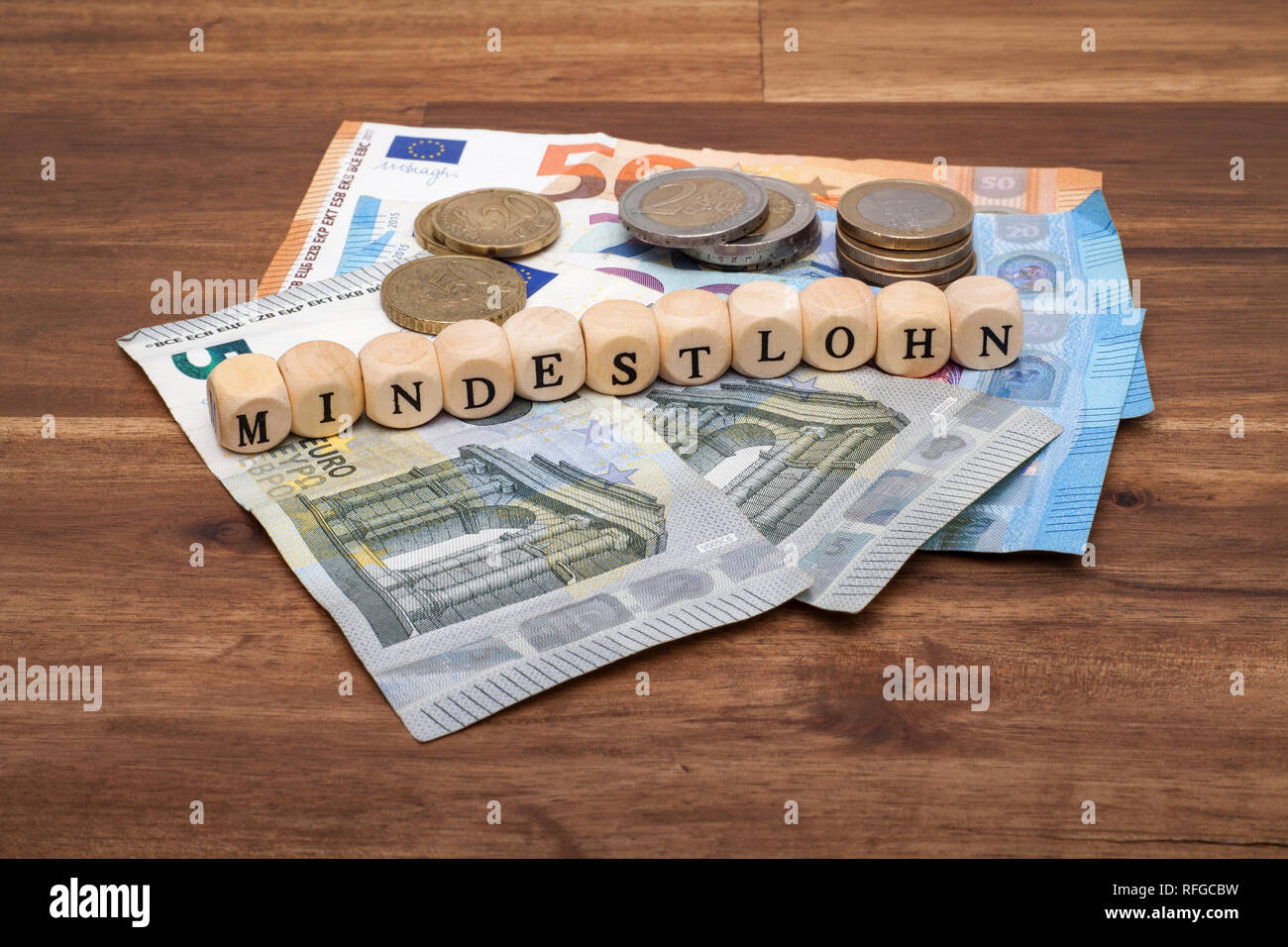 Die Euro Geldscheine und Münzen liegen auf dem Tisch mit dem Wort Mindestlohn Stock Photo