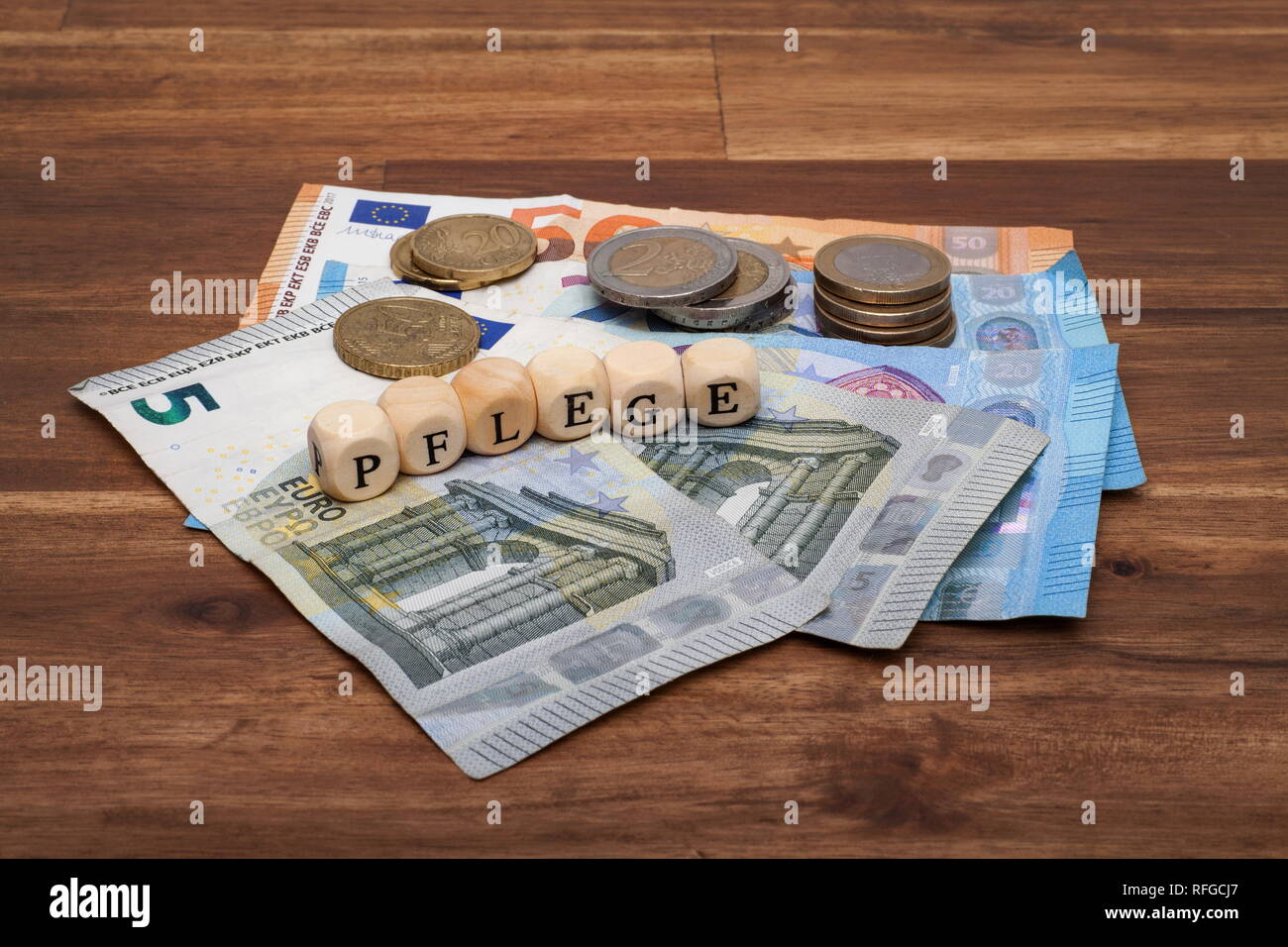 Die Euro Geldscheine und Münzen liegen auf dem Tisch mit dem Wort Pflege Stock Photo