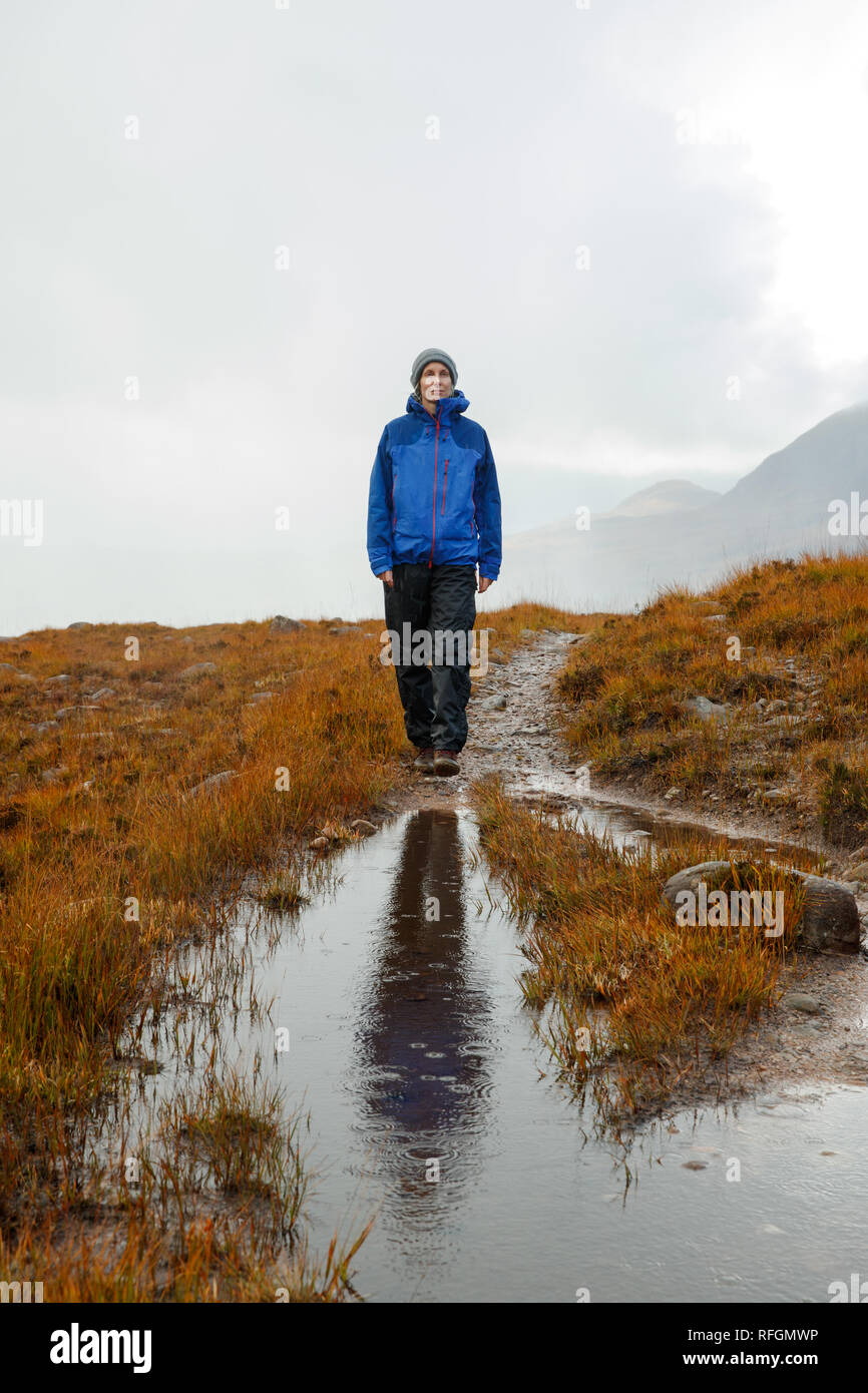 A person walking in Scottish countryside near the Allt Coire Rooill river in Torridon, Scotland Stock Photo
